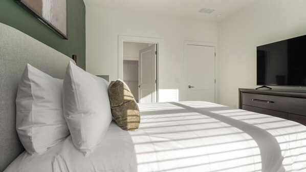 Une chambre à coucher avec un lit, des oreillers, une télévision et une commode.