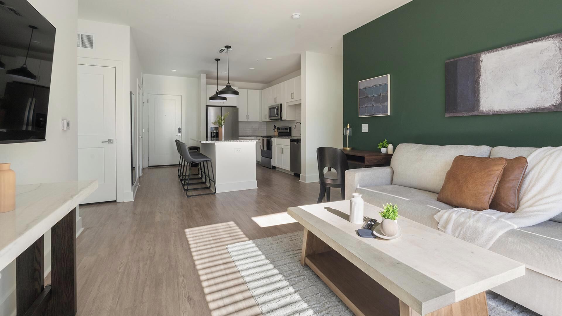 A modern living space with a kitchen, dining area, and a sofa with cushions.