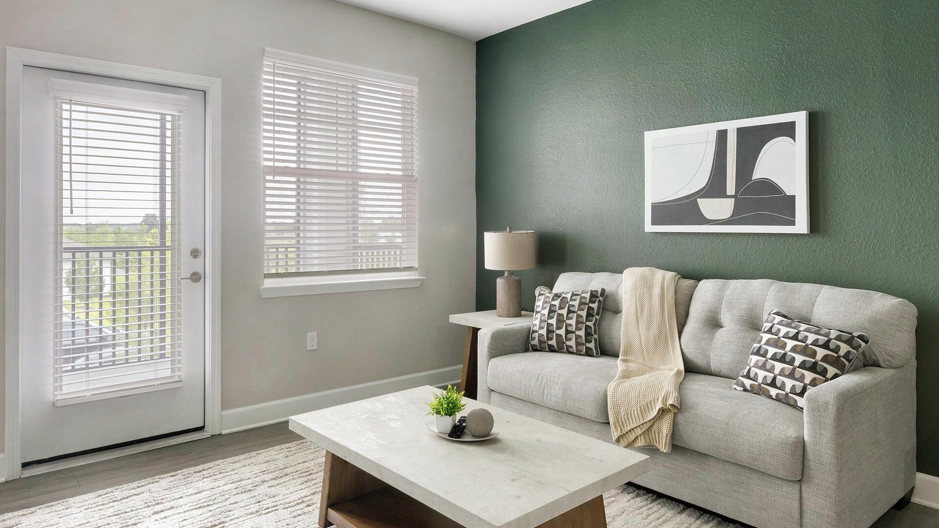A living room with a grey sofa, a coffee table, a lamp, and a painting on the wall.