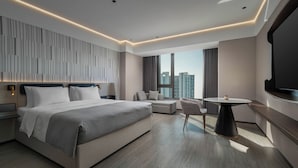Une chambre d’hôtel moderne dotée d’un grand lit, d’un coin salon, d’une table à manger et d’un téléviseur.