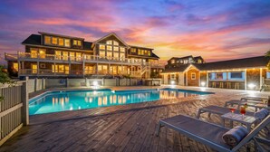 A large, multi-story hotel with a swimming pool and outdoor seating area. - Oceanfront Estate | Sleeps 40 | Weddings & Retreats | 18BR | OBX (Corolla)