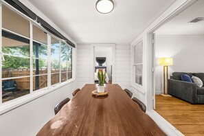 Ein Esszimmer mit Holztisch, weißen Wandverkleidungen und Blick ins Freie.