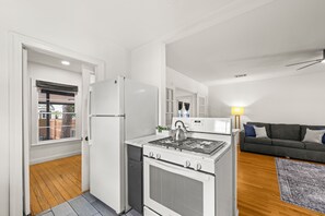 Eine kompakte Küche mit Herd, Kühlschrank und Essbereich inklusive Sofa und Teppich.