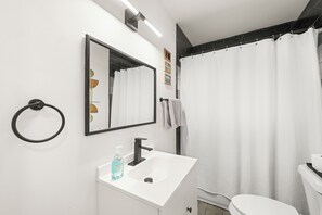 Un baño moderno con un lavamanos blanco, un grifo negro y un espejo encima.