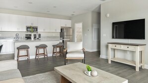 Una cocina moderna con armarios blancos, una isla central y un comedor con mesa y sillas.