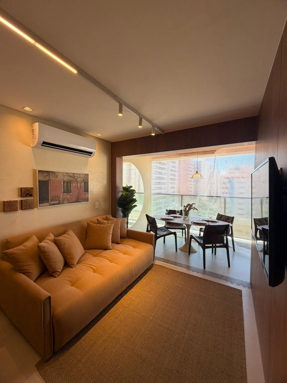 Una sala moderna con sofá, mesa de comedor, sillas y televisor.