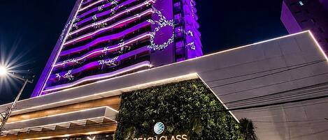 A tall building with a neon-lit facade and a sign for 'Beach Class' hotel.