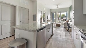 A modern kitchen with a large island, stainless steel appliances, and a view to the living area. - Landing | Amazing 1BD, Gym, Clubhouse (Jacksonville)