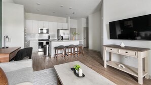 A modern kitchen with white cabinets, stainless steel appliances, and a central island with bar stools. - Landing | Spectacular 1BD, Gym, Clubhouse (Jacksonville)