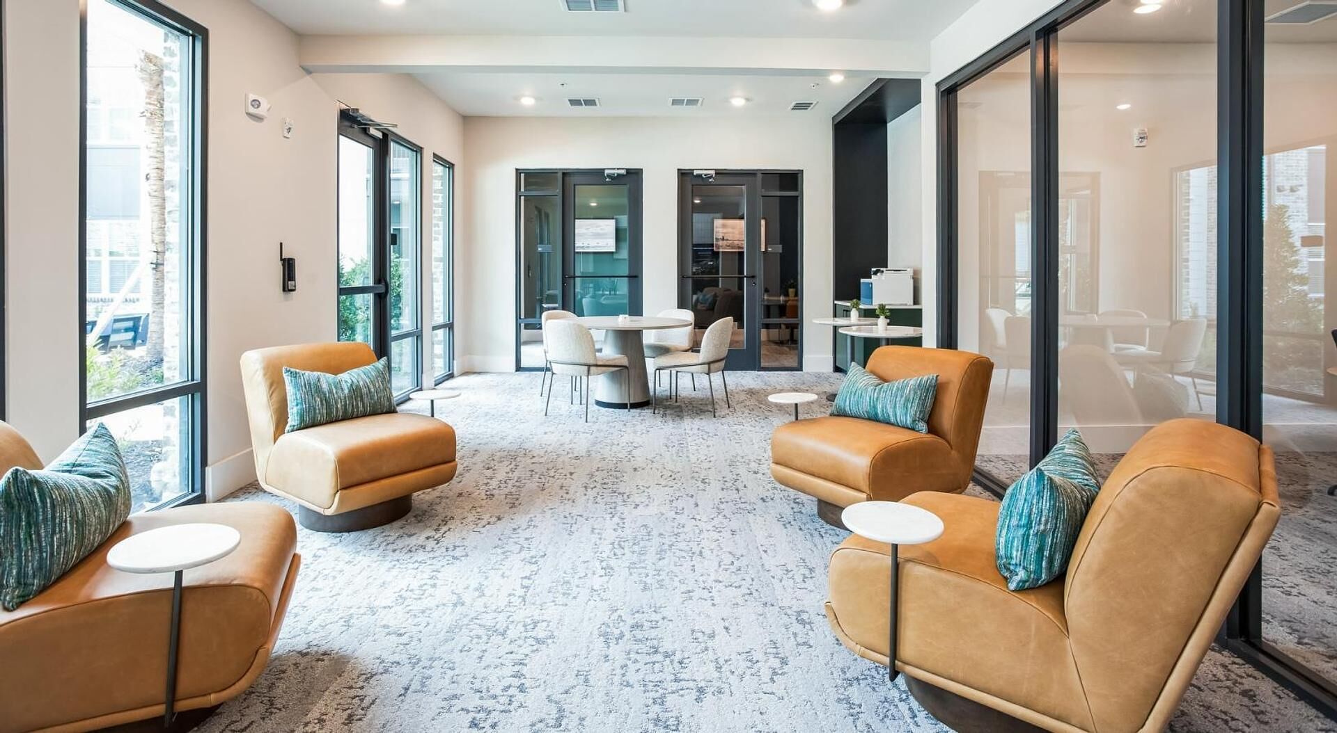 Una moderna zona relax con divani in pelle, tavoli rotondi e ampie finestre.