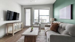 Una sala de estar moderna con un sofá, una mesa de centro, un televisor y una ventana con persianas.
