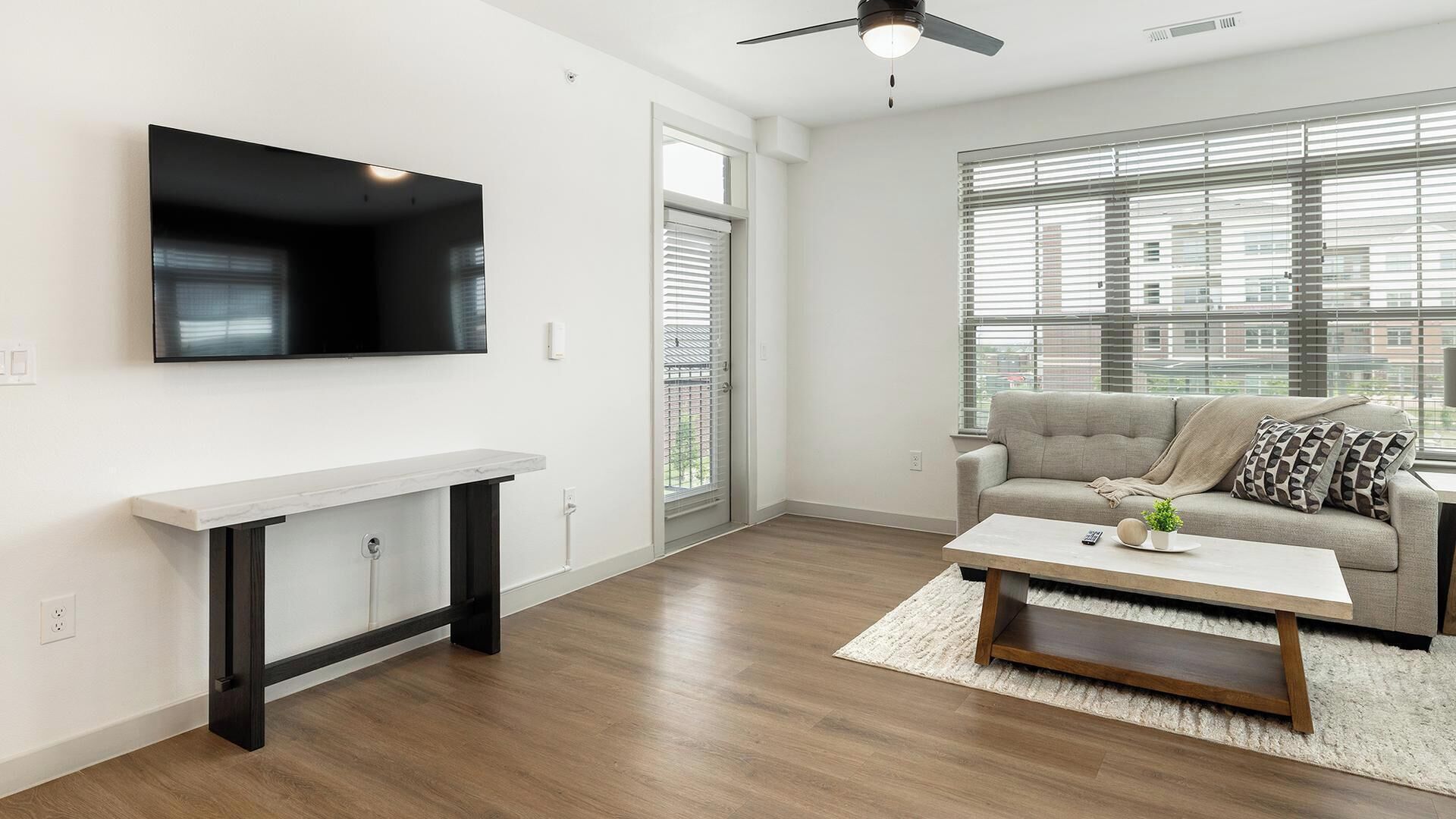 A modern living room with a flat-screen TV, a white console table, a beige sofa, and a coffee table.