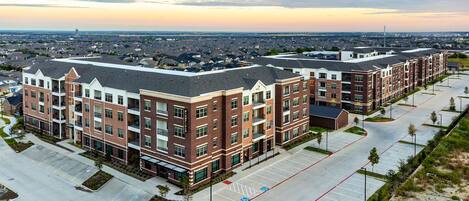 A multi-story residential building with a parking lot and a clear view of the surrounding area.