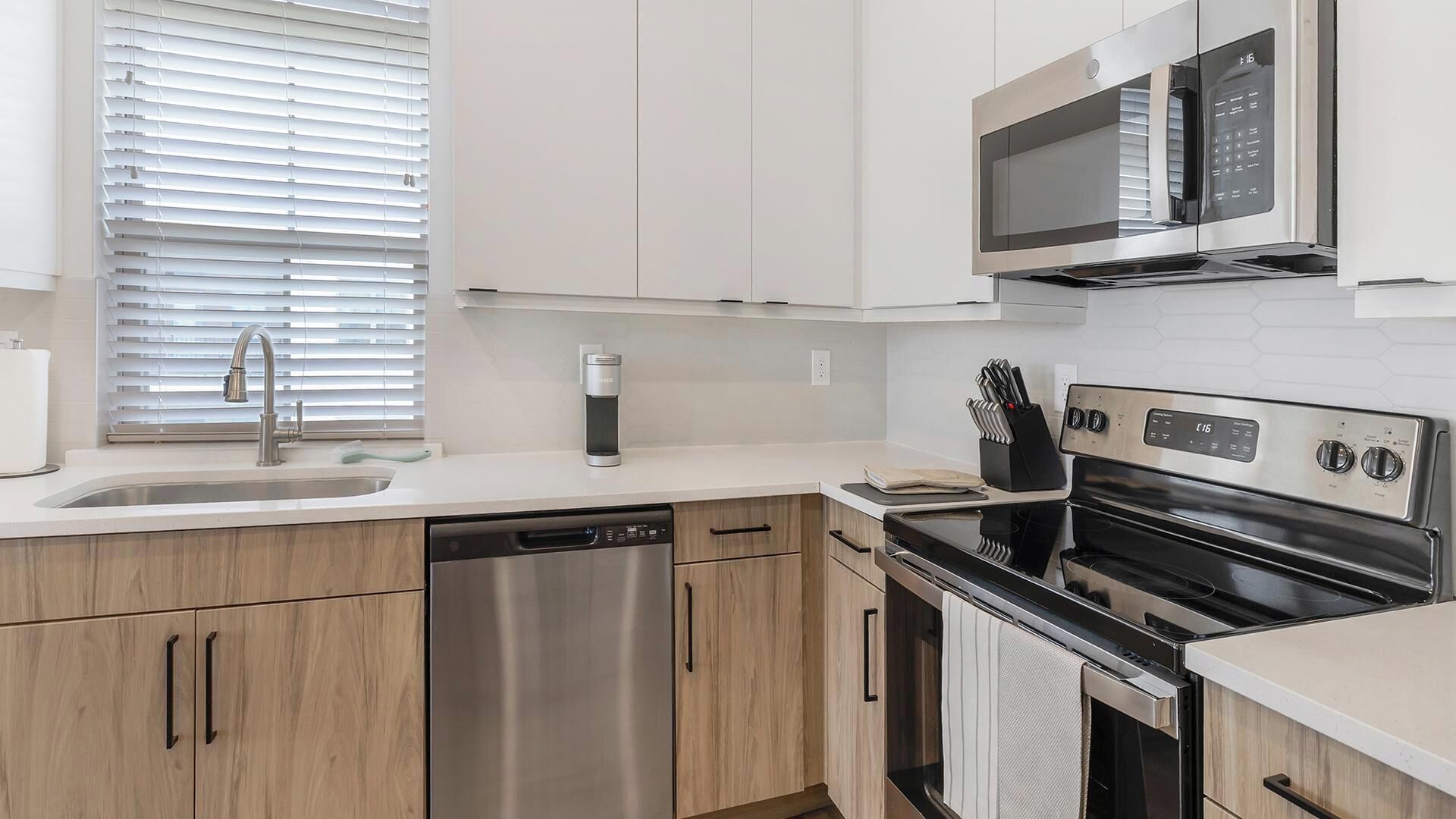 Una cocina moderna con electrodomésticos de acero inoxidable, armarios de madera y lavavajillas.