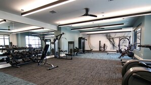 Uma academia com equipamentos de ginástica, espelhos e piso coberto de carpete.