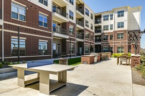Un immeuble d’appartements à plusieurs étages doté d’espaces extérieurs aménagés pour s’asseoir, d’un barbecue et d’une pelouse bien entretenue.