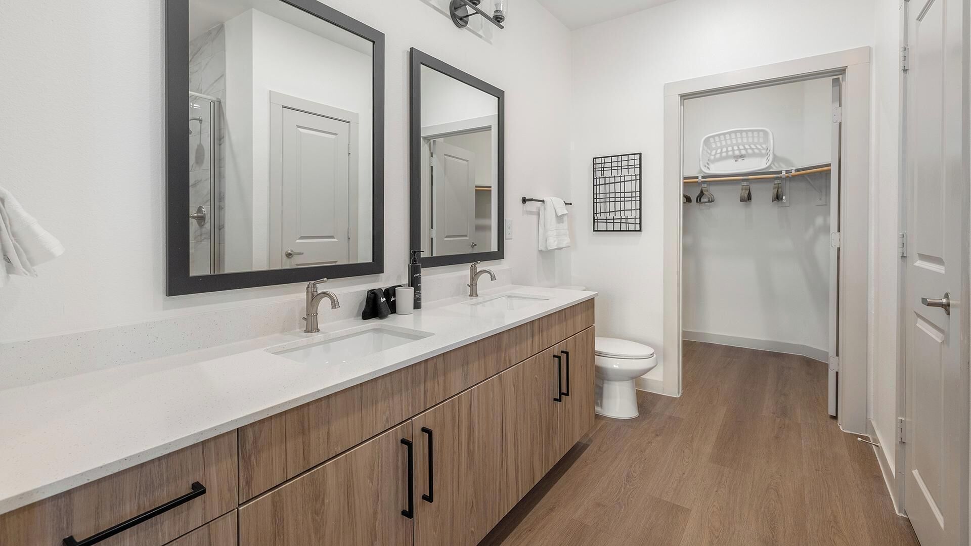 Une salle de bain moderne avec deux lavabos, des toilettes et un dressing.