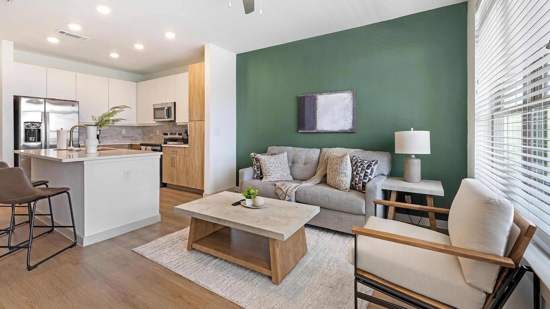 Ein modernes Apartment mit Küche, Wohnbereich und einer Wand in Grüntönen.