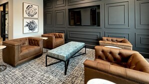 A modern living room with leather sofas, a coffee table, and artwork on the wall. - Landing | Amazing 1BD, Courtyard, Clubhouse (Celina)