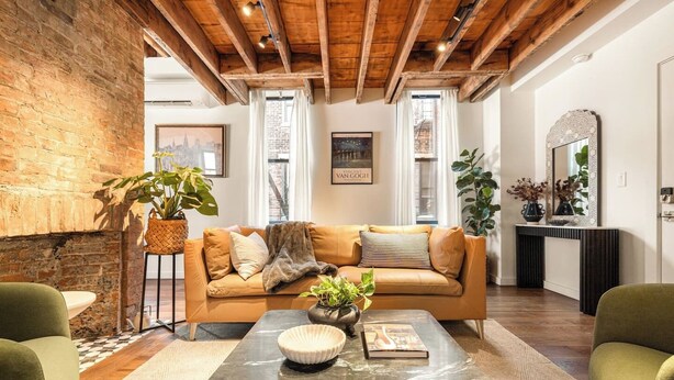 A living room with a sofa, a coffee table, and a brick wall. - 6BR Retreat, Walkers Paradise Near Washington Park (Cincinnati)