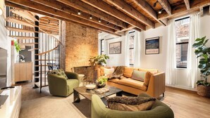 A modern living room with a spiral staircase, a fireplace, and a large window with curtains. - 6BR Retreat, Walkers Paradise Near Washington Park (Cincinnati)
