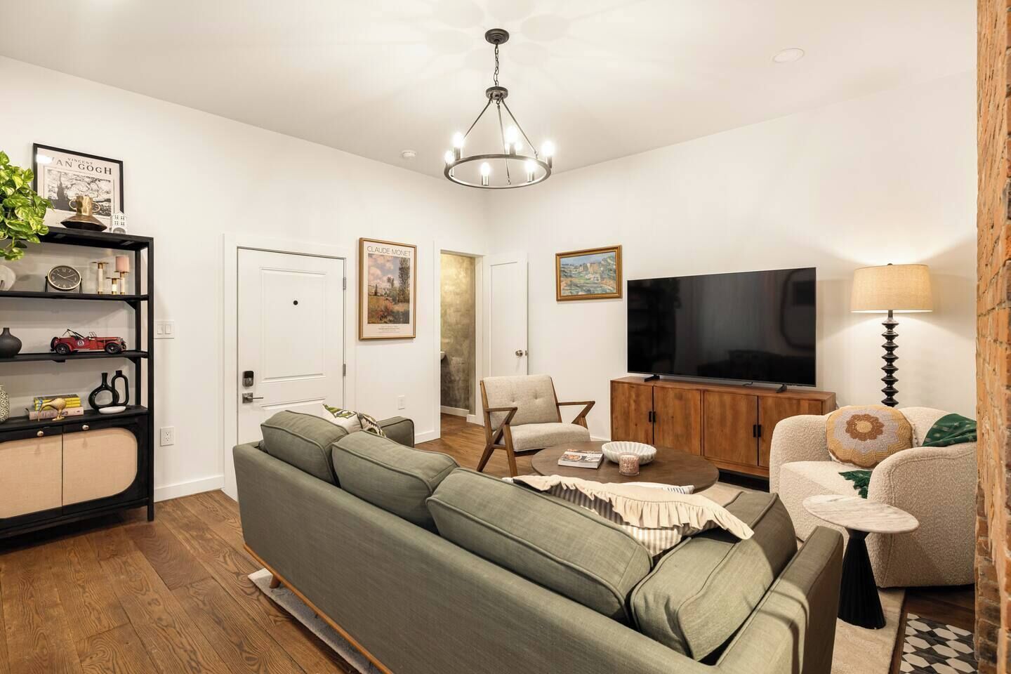 A living room with a sofa, armchairs, a TV, and a bookshelf.