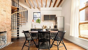 A modern kitchen with a dining area, wooden staircase, and a view of the city. - 6BR Retreat, Walkers Paradise Near Washington Park (Cincinnati)