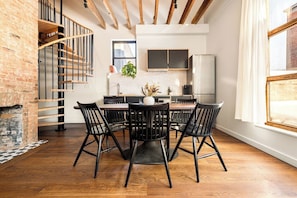 A modern kitchen with a dining area, wooden staircase, and a view of the city. - 6BR Retreat, Walkers Paradise Near Washington Park (Cincinnati)