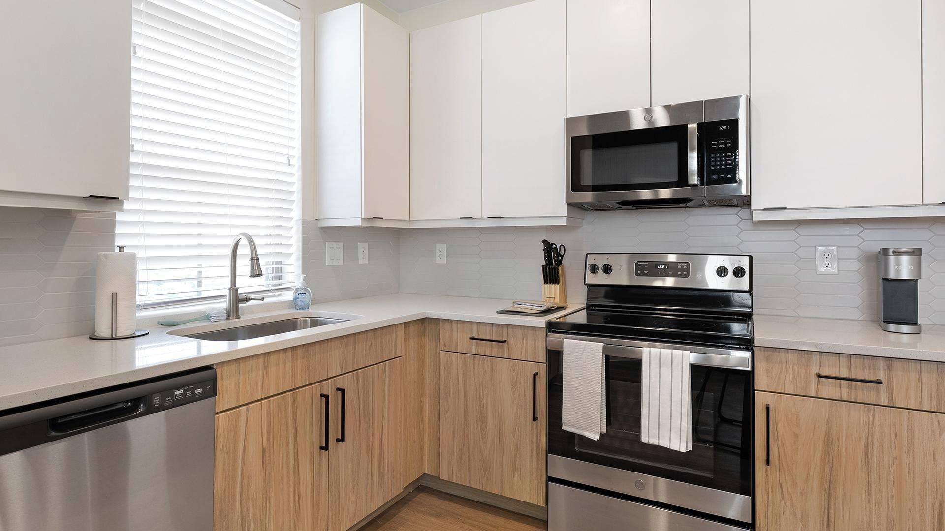 A modern kitchen with white cabinets, stainless steel appliances, and a dishwasher.