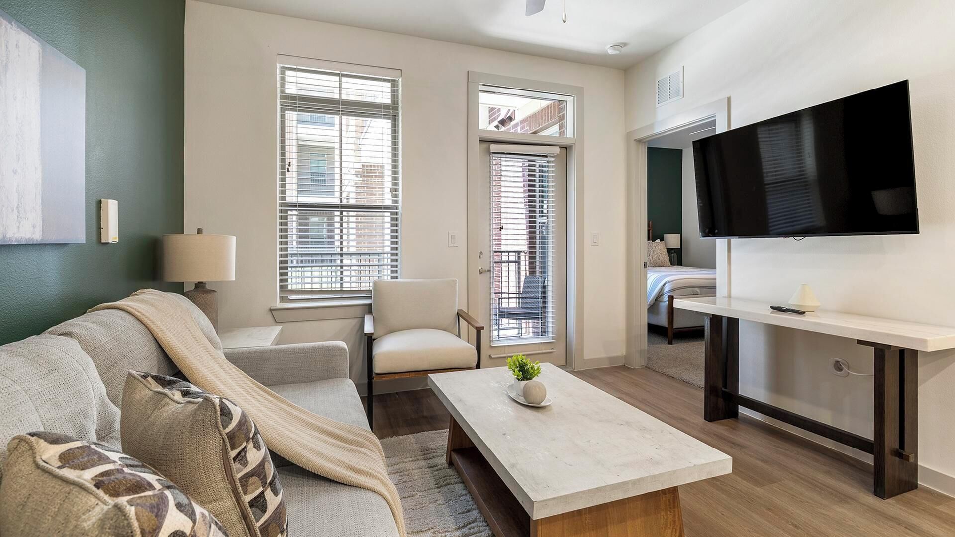 A modern living room with a sofa, a coffee table, a TV, and a window with blinds.