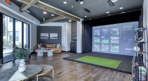A modern interior with a large screen displaying games, a sofa, and a coffee table. - Landing | Incredible 1BD, Yoga Studio (San Antonio)