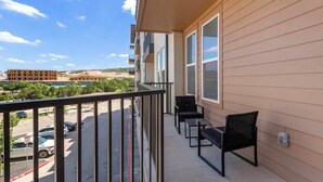 A balcony with a metal railing, two chairs, and a table. - Landing | Incredible 1BD, Yoga Studio (San Antonio)