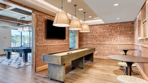Uma mesa de bilhar, pingue-pongue e um bar com televisão na parede.