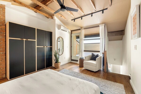 A bedroom with a bed, a chair, a mirror, a plant, and a wardrobe. - 7BR Retreat, Walkers Paradise Near Washington Park (Cincinnati)