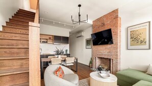Een moderne woonkamer met een open haard, een eethoek en een trap.