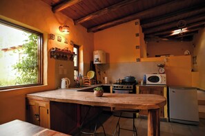 A kitchen with a wooden counter, stove, microwave, and refrigerator.