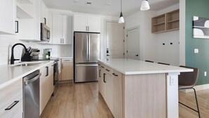 Eine moderne Küche mit weißen Schränken, Edelstahlgeräten und einer Holztheke.