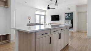 Eine moderne Küche mit einer zentralen Kochinsel, eingebauten Schränken, einem Deckenventilator und einem an der Wand befestigten Fernseher.