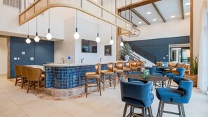 Un moderno vestíbulo de hotel con zona de bar, asientos y una escalera.