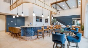 A modern hotel lobby with a bar area, seating, and a staircase. - Landing | Spectacular 2BD, Yoga Studio (San Antonio)