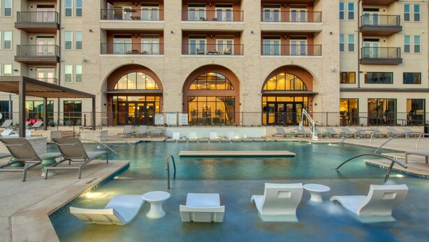 Un hotel con piscina, sillones de descanso y un patio cubierto.