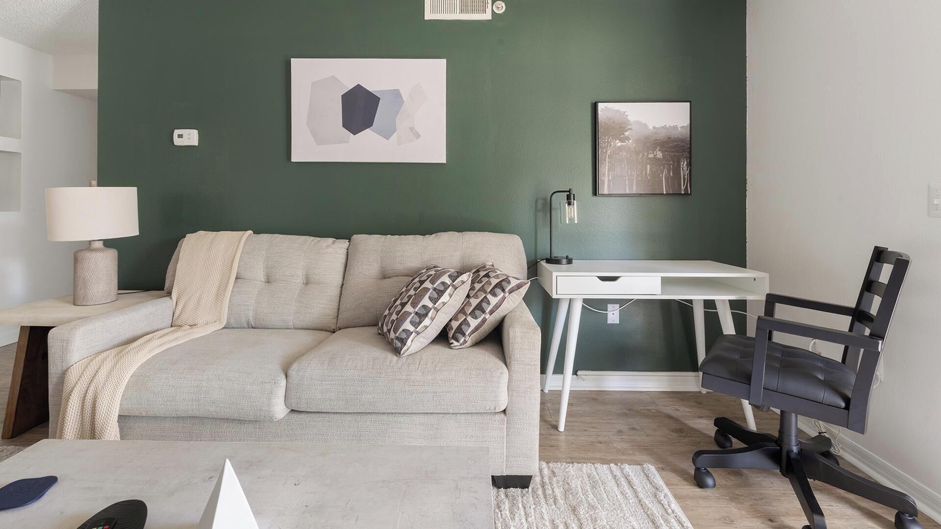 A modern living room with a sofa, a desk, and a chair.
