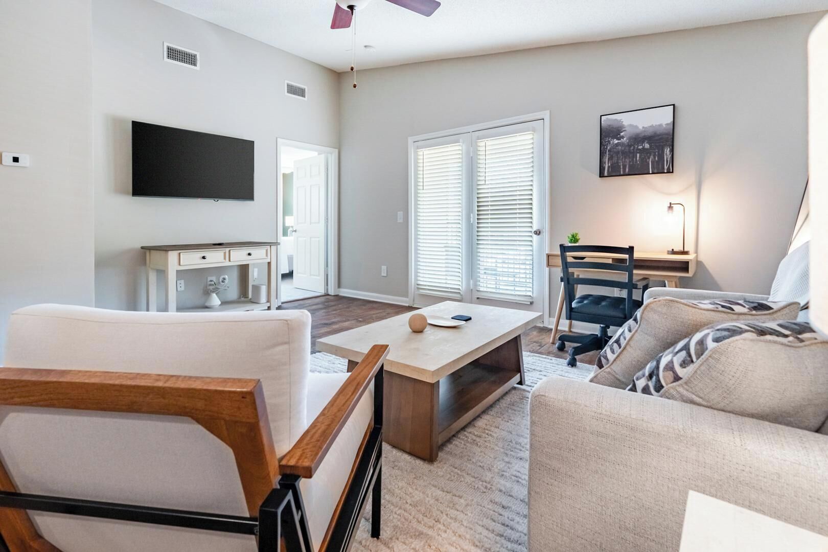 A modern living room with a flat-screen TV, a wooden coffee table, a sofa, and a chair.