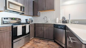 Eine moderne Küche mit dunklen Holzschränken, Edelstahlgeräten und einer weißen Arbeitsplatte.