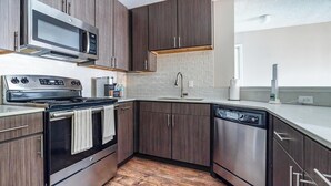 Une cuisine moderne avec des meubles en bois foncé, des appareils électroménagers en acier inoxydable et un plancher en bois.