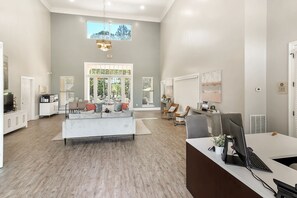 A spacious living area with a large sofa, a dining table, and a computer desk. - Landing | Amazing 2BD, Pool, Gym (Biloxi)