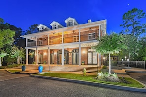 A two-story building with a balcony, large windows, and a well-lit entrance. - Landing | Spectacular 3BD, Pool, Gym (Biloxi)
