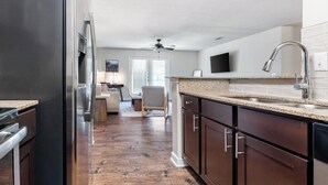 A modern kitchen with dark wood cabinets, a stainless steel refrigerator, and a granite countertop. - Landing | Spectacular 3BD, Game Room, Clubhouse (Gulf Hills)