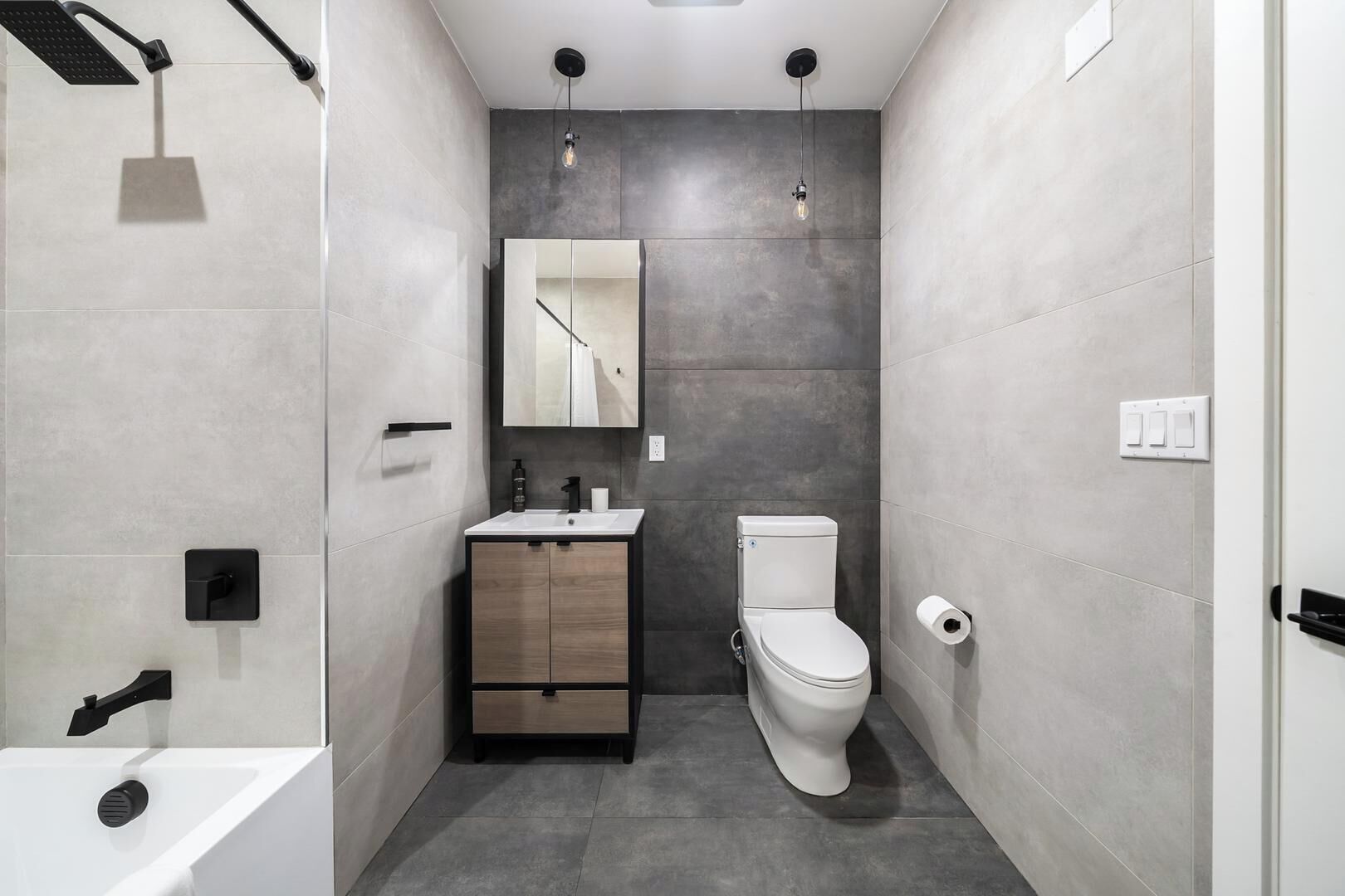A modern bathroom with a shower, sink, toilet, and a mirror.