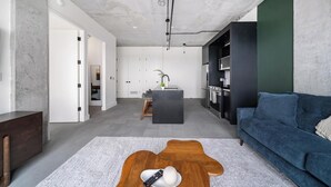 Una sala moderna con un sofá, una mesita de centro y una cocina al fondo.
